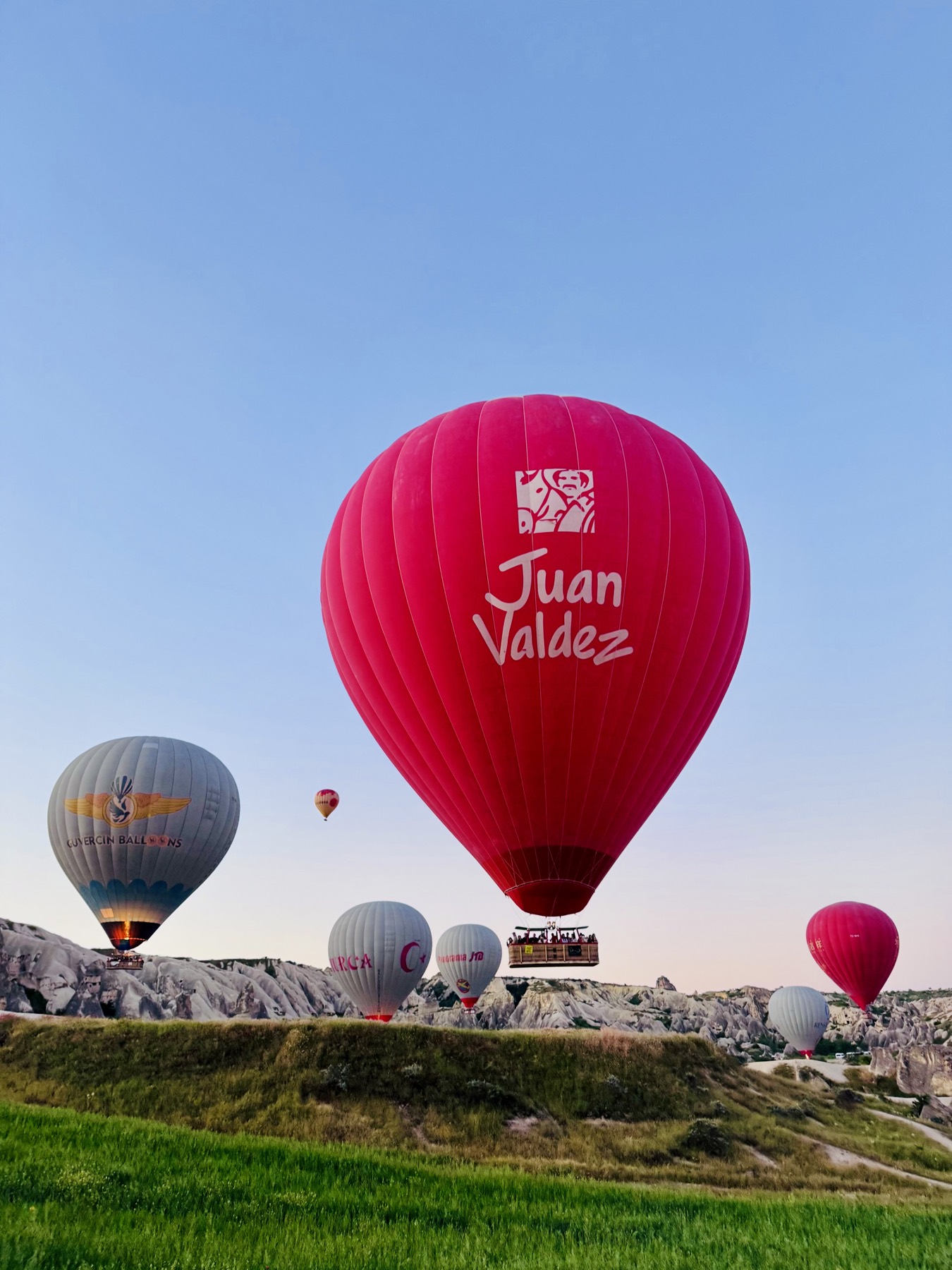 Hot air balloons including a red Juan Valdez balloon over Cappadocia